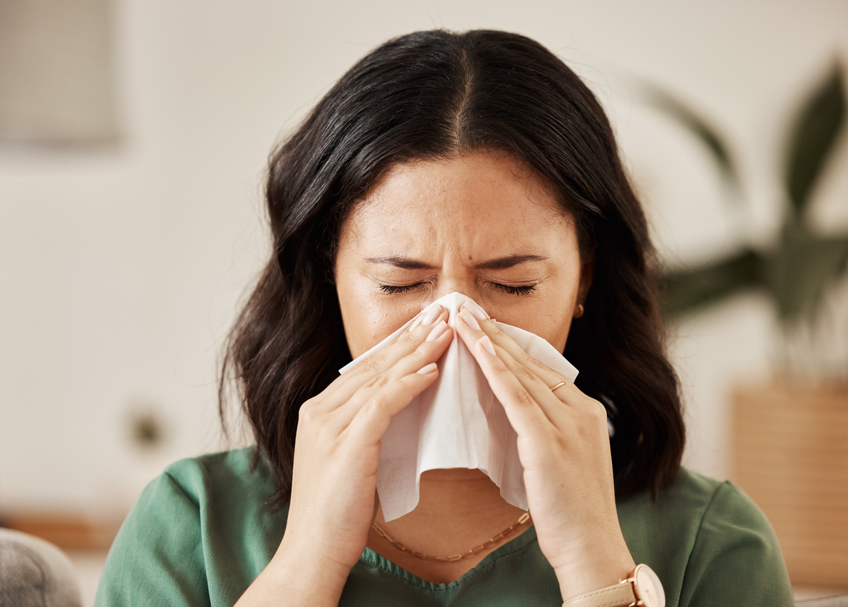 A woman in a green shirt blowing her nose